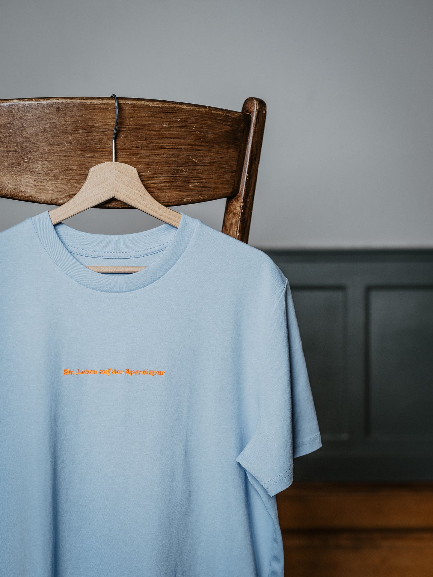T-Shirt Ein Leben auf der Aperolspur hängt am Stuhl